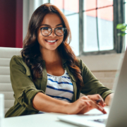 a woman is sitting at a desk using a laptop computer