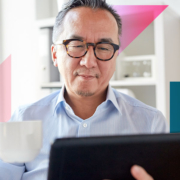 a man holding a cup of coffee while looking at a tablet