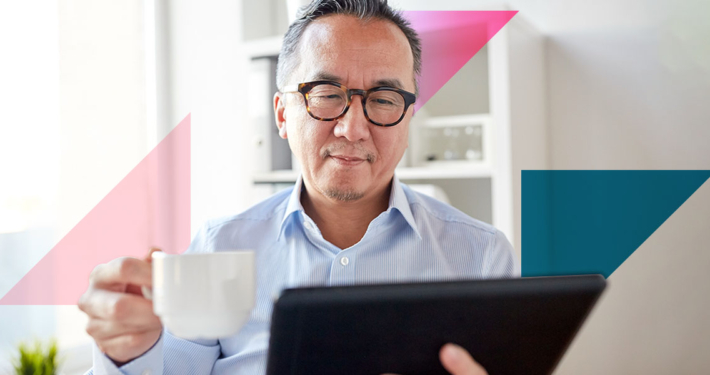 a man holding a cup of coffee while looking at a tablet