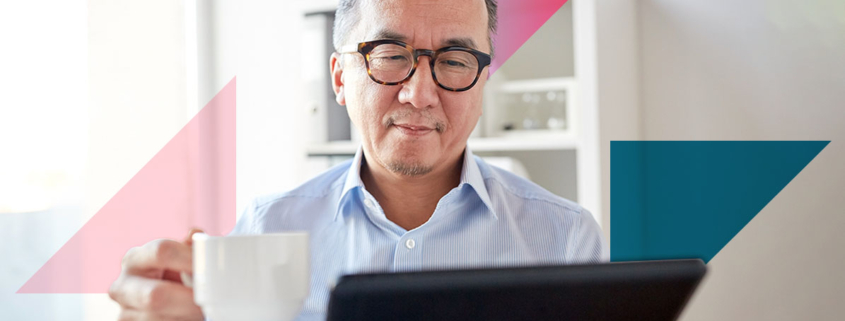 a man holding a cup of coffee while looking at a tablet