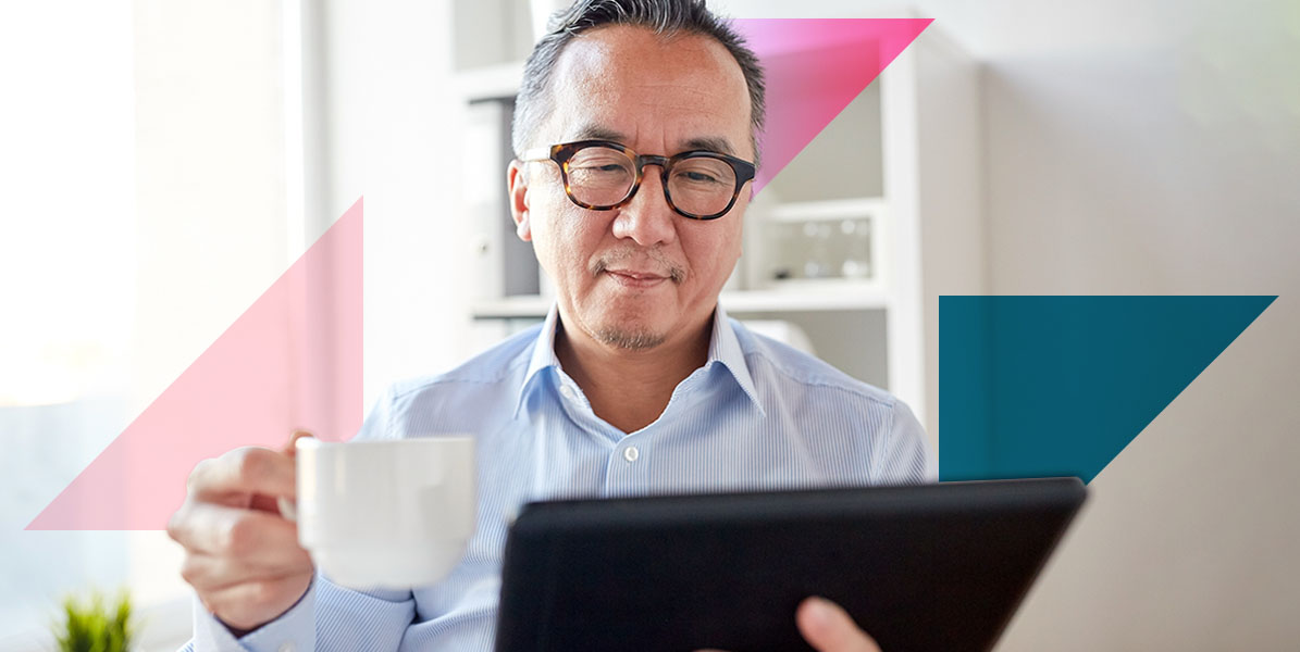 a man holding a cup of coffee while looking at a tablet