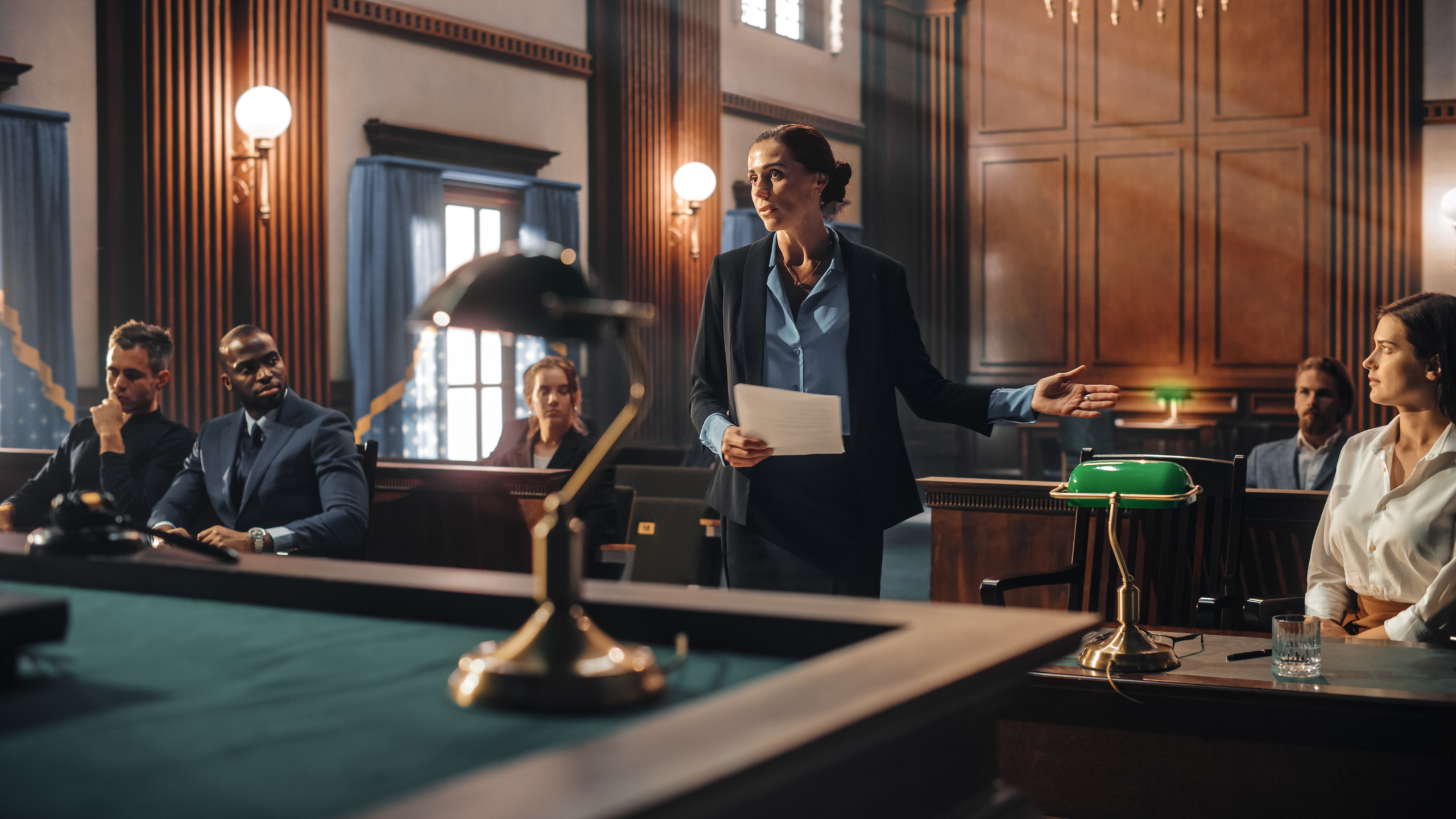 a woman is giving a speech in front of a group of people in a courtroom