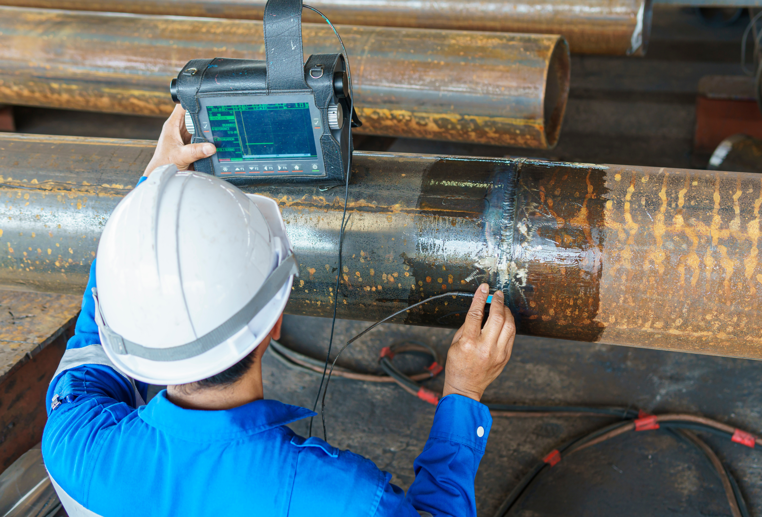 a man wearing a hard hat is using a device that says 'ultrasonic' on it