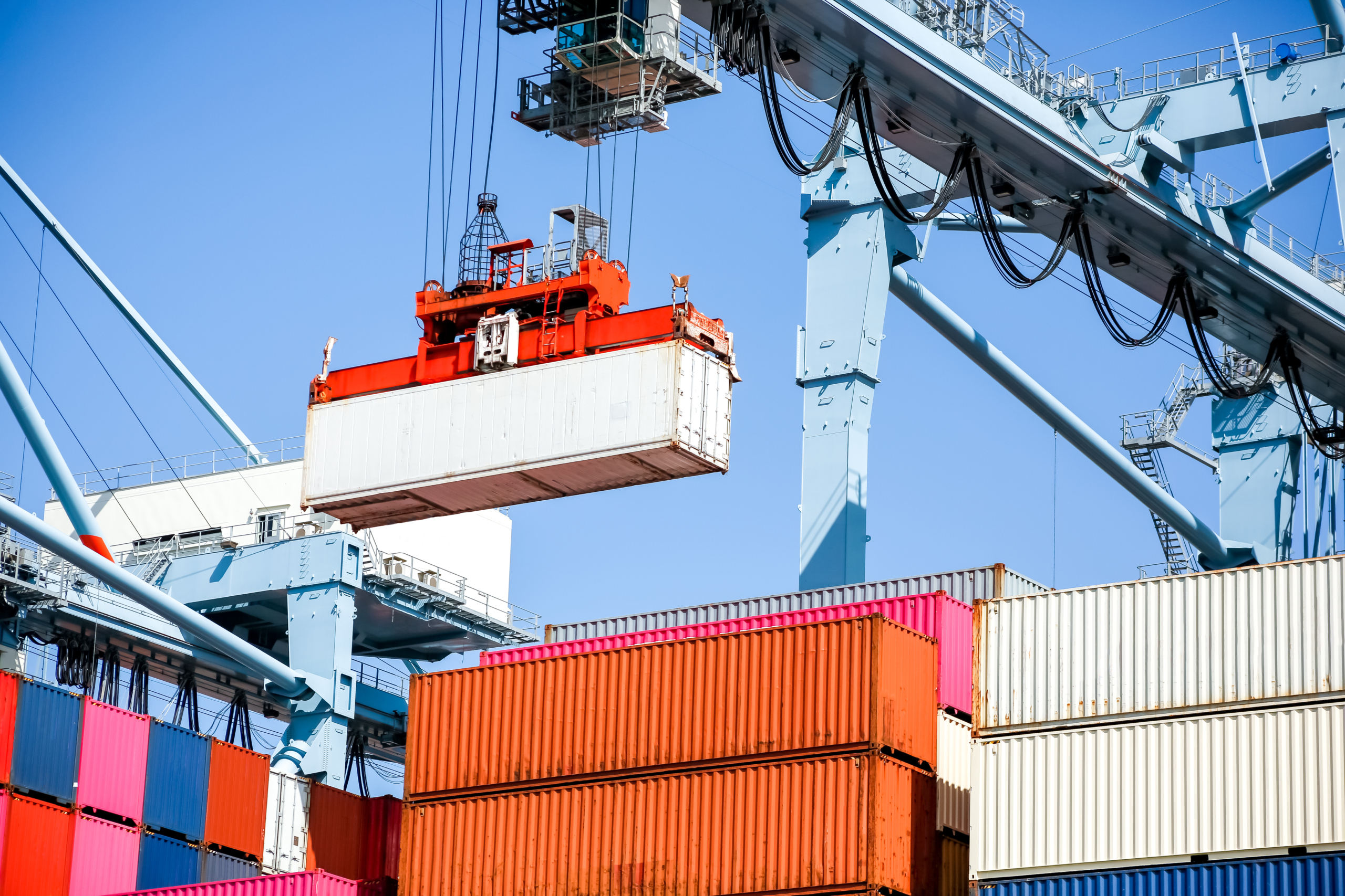 a crane lifts a container into a stack of containers