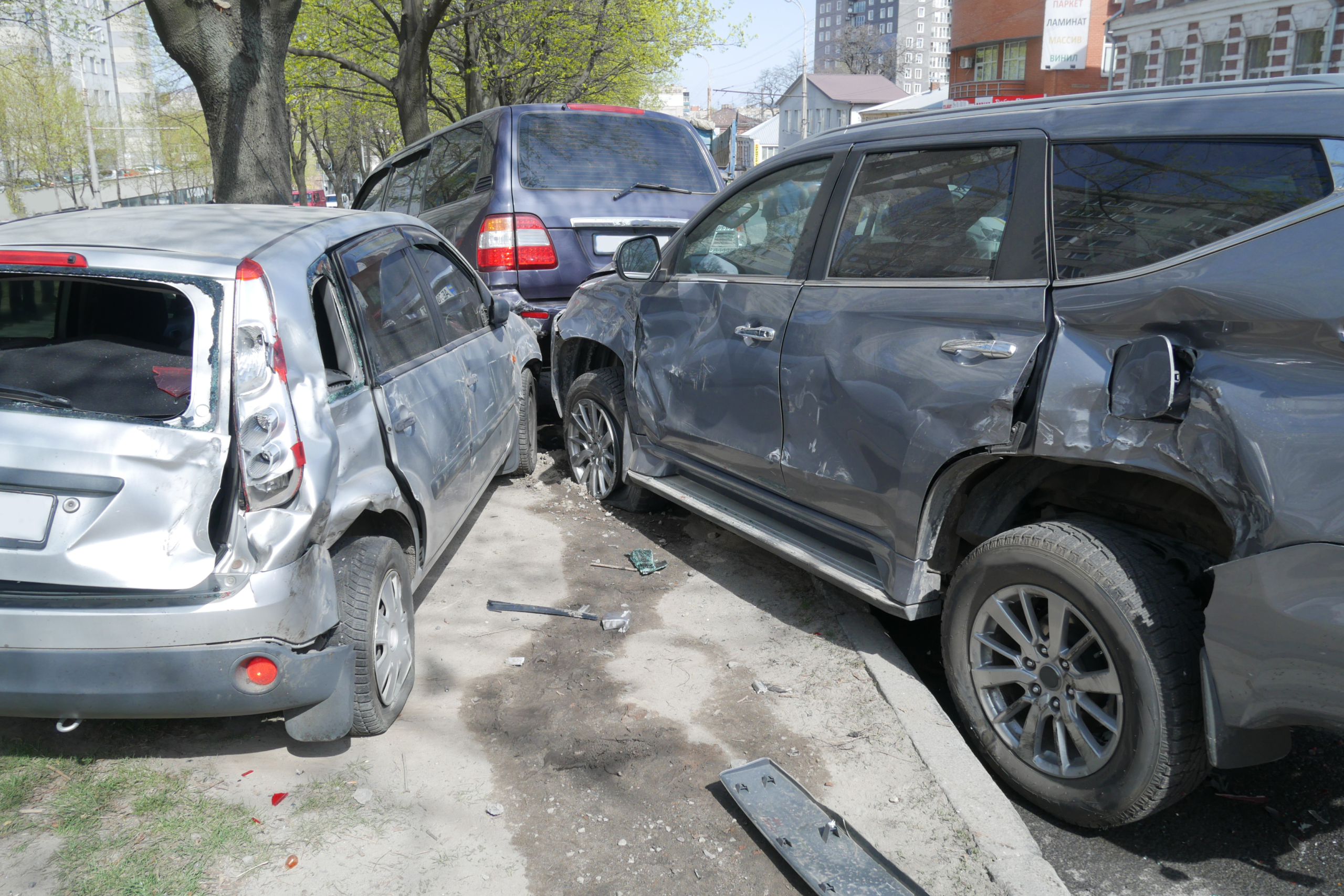 a silver car with a broken windshield is parked next to a gray suv