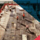 Aerial view of construction workers in safety vests and hard hats installing a dense steel rebar grid