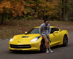 a man leans against a yellow sports car with the word corvette on the front