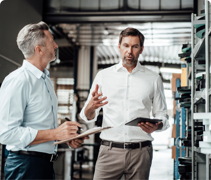 a man holding a tablet talks to another man holding a clipboard