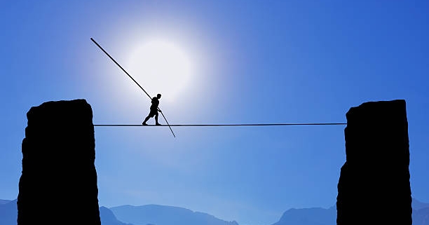 a man is walking on a tightrope with mountains in the background