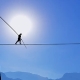 a man is walking on a tightrope with mountains in the background