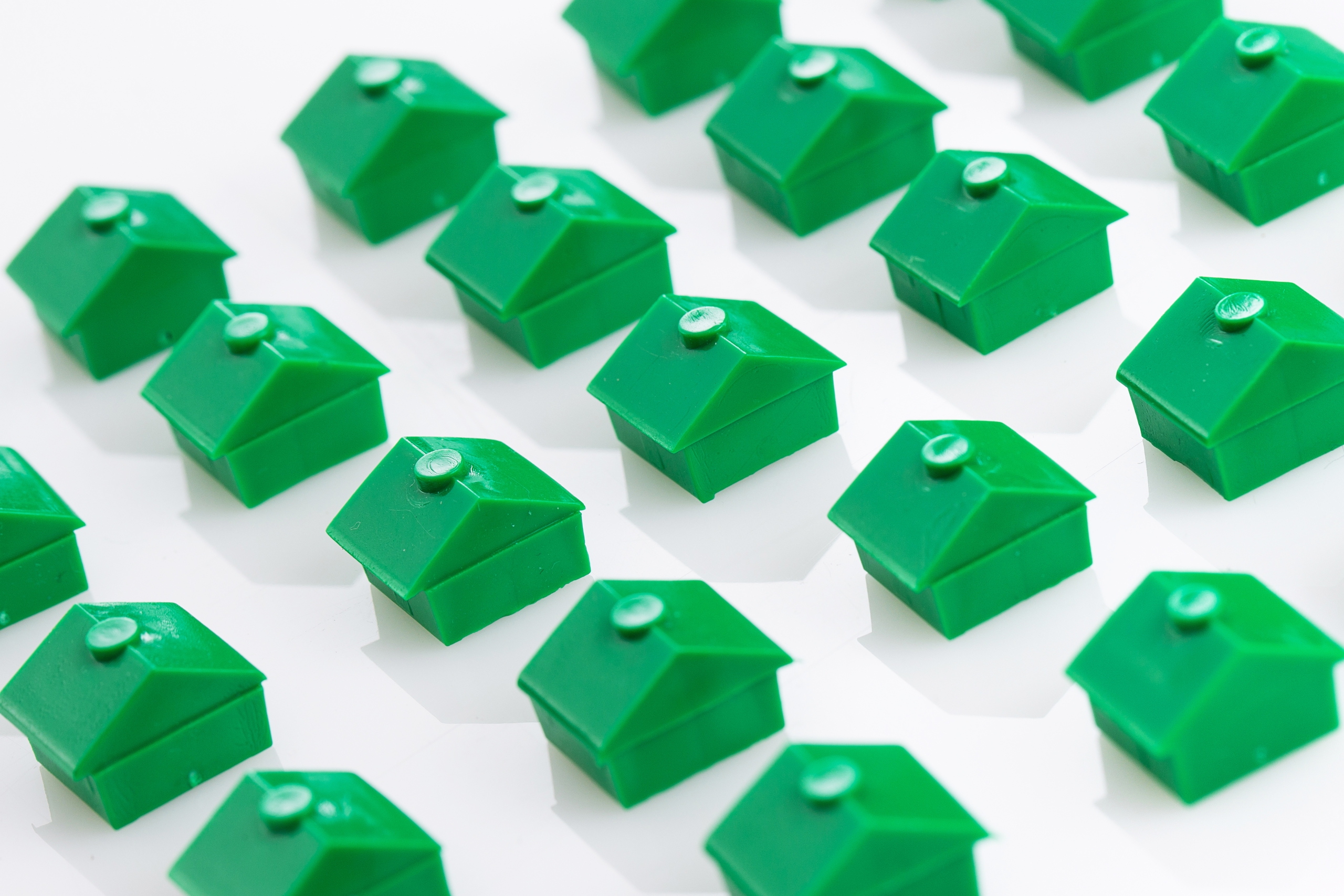 a bunch of green houses are lined up on a white surface