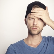 a man wearing a baseball cap holds his hand to his forehead