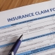 a blue pen sits on top of an insurance claim form